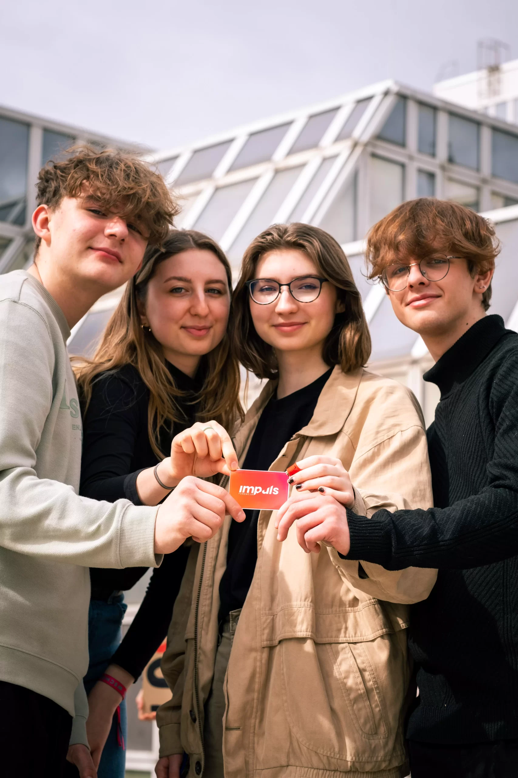 cztery osoby trzymają wizytówkę z napisem impuls